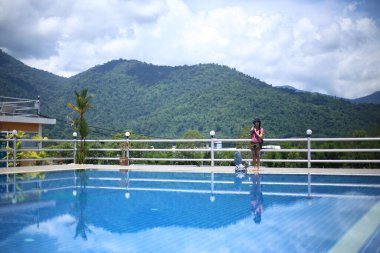 Havuz kenarında dağ manzaralı bir kadın.