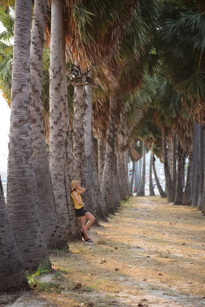 萨塔希 一个站在路边的棕榈树花园里的女人 — 图库照片