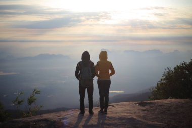 Erkekler ve kadınlar uçurumun kenarında, Phu Kradueng Ulusal Parkı, Loei, Tayland 'da güneşin doğuşunu bekliyorlar.