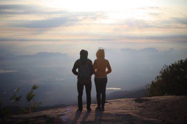 Erkekler ve kadınlar uçurumun kenarında, Phu Kradueng Ulusal Parkı, Loei, Tayland 'da güneşin doğuşunu bekliyorlar.