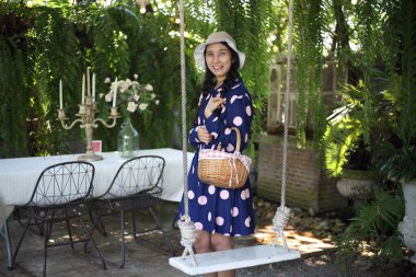 Bahçede salıncağın yanında duran sepeti tutan bir kadın.