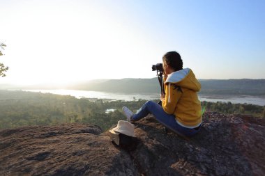 Pha Tam Ulusal Parkı, Ubon Ratchathani, Tayland 'da oturan ve resim çeken bir kadın..