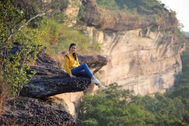 Pha Tam Ulusal Parkı 'nda uçurumda oturan kadın, Ubon Ratchathani, Tayland.