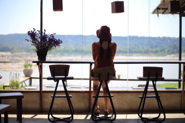 Bir kadın camdan nehri seyrediyor.