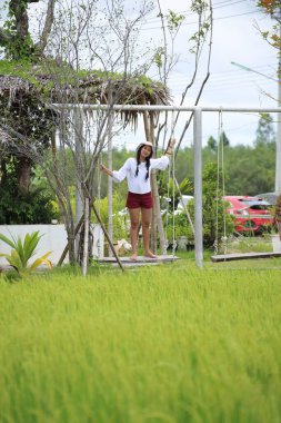 Tayland 'da bir pirinç tarlasında salıncakta sallanan bir kadın.