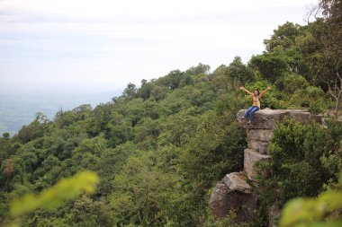 Tayland, Chaiyaphum 'daki Mor Hin Khao Milli Parkı' nda bir uçurumda oturan kadın.