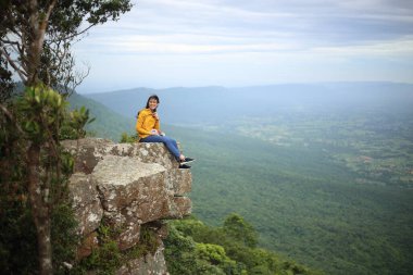 Tayland, Chaiyaphum 'daki Mor Hin Khao Milli Parkı' nda bir uçurumda oturan kadın.