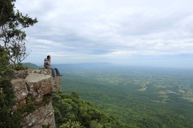 Tayland, Chaiyaphum 'daki Mor Hin Khao Ulusal Parkı' nda bir uçurumda oturan adam.