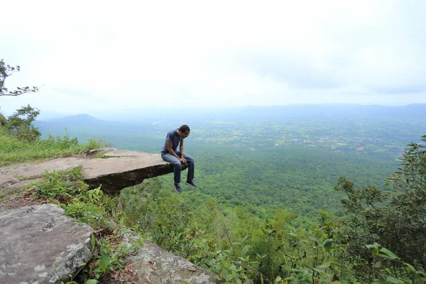 Man sitting at the edge of a cliff Sai Thong National Park in Chaiyaphum, Thailand.