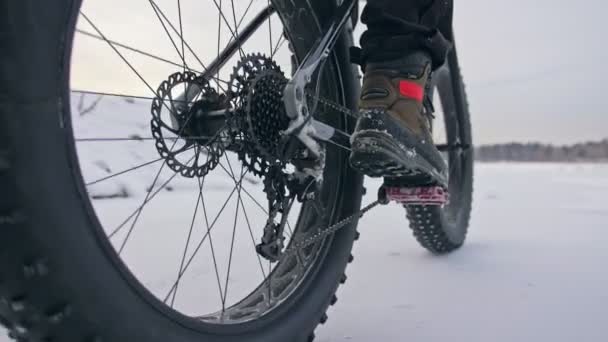 Profesionální sportovec extrémní biker jezdecké tuku kolo v venkovní. Cyklisté jezdí v zimě sníh lese. Člověk dělá zkušební trik wheelie na horské kolo s velkými pneumatiky v helmy a brýle.