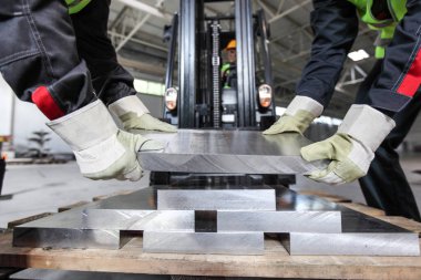 CNC makine atölyesinde alüminyum alan işçiler