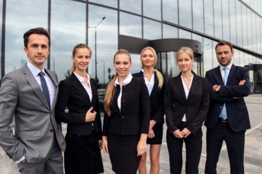 Başarılı iş adamlarının portresi modern ofis binasının yakınında birlikte duruyorlar.