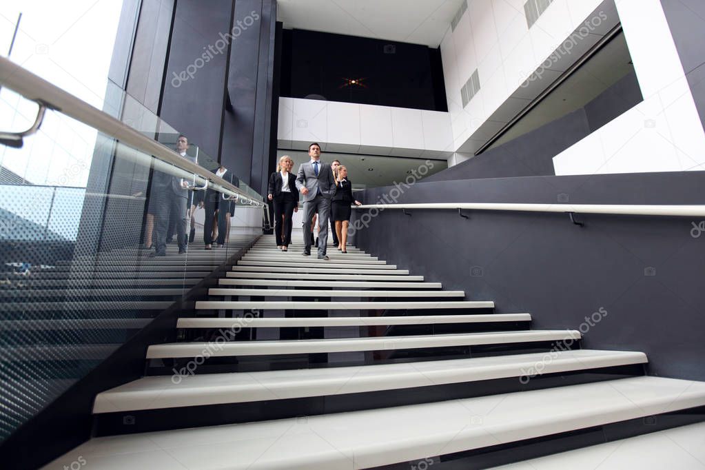Group of business people walking and taking at stairs in an office building