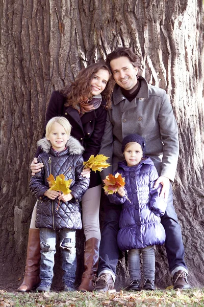 幸福的家庭 在秋天公园附近一棵大树的树干 — 图库照片