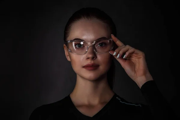 Beautiful woman with transparent futuristic glasses on dark background