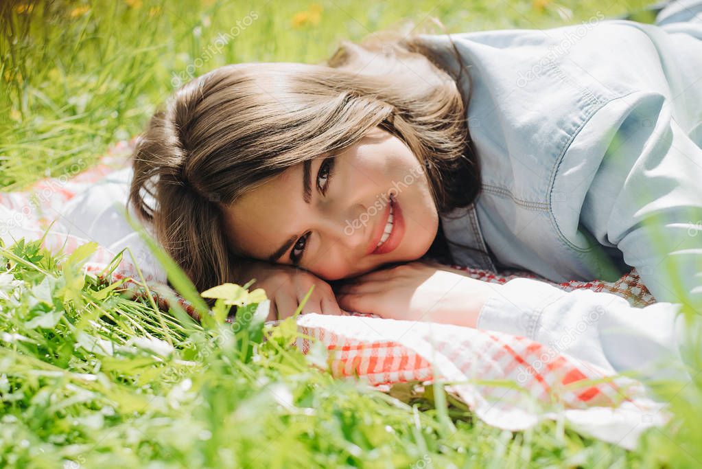 Pretty young woman laying in the grass and smiling