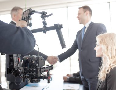 Videographer using steadycam, making video of business people shaking hands clipart