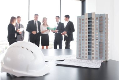 Mimarlar ve yatırımcıların masadaki modern çok katlı konut modeline baktıkları iş toplantısı
