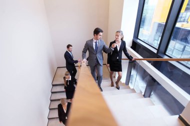 Bir grup iş adamı bir ofis binasında yürüyen ve merdivenlerde yürüyen