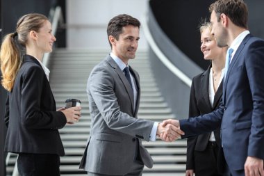 İş adamları ofis lobisinde durup konuşuyorlar.