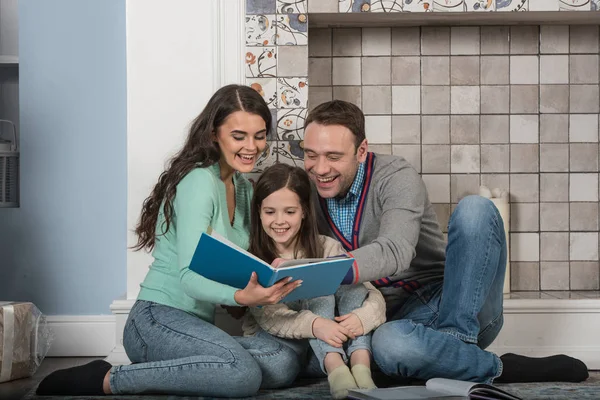 全家福的快乐的父母和他们的女儿一起在家里看书 — 图库照片