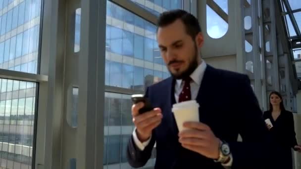 空港ターミナルでウォーキング コーヒーを飲みながら 携帯電話を使用してビジネスの男性 — ストック動画
