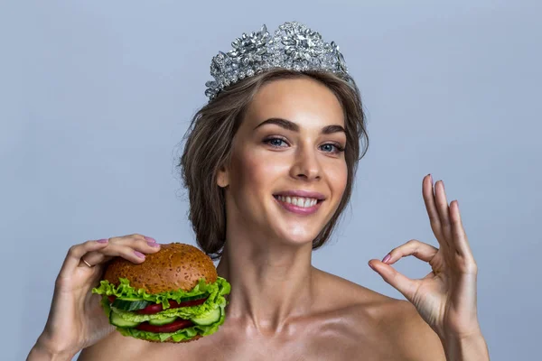 野菜と表示 サインで作られた完全菜食主義のハンバーガーを保持している頭の上の王冠と美しい若いブロンドの女性の肖像画 — ストック写真