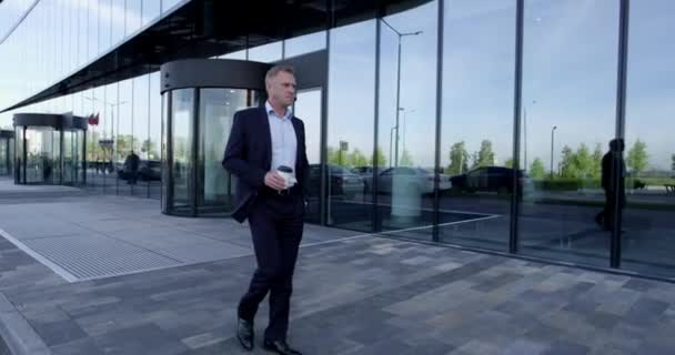 Älterer Geschäftsmann Spaziert Draußen Bürogebäude Entlang Und Hält Kaffee Zum — Stockvideo