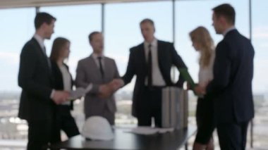 Mimarlar ve yatırımcıların masadaki modern çok katlı konut modeline baktıkları iş toplantısı