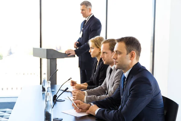 Participantes Conferência Imprensa Sentados Mesa Uma Fileira Orador Falando Tribuno — Fotografia de Stock