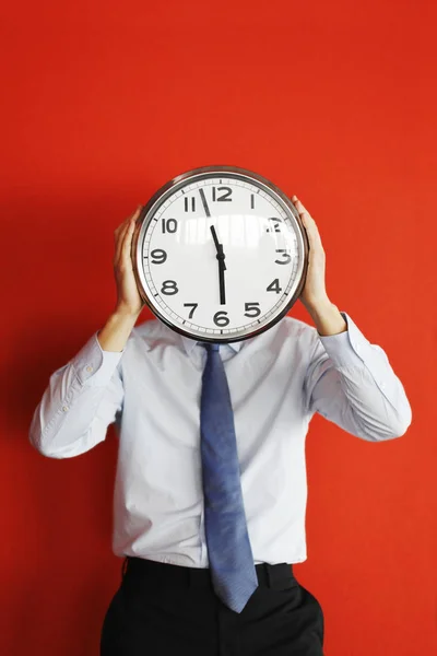Hombre Negocios Sosteniendo Gran Reloj Cubriendo Cara Sobre Fondo Rojo — Foto de Stock