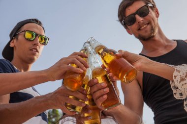 Mutlu genç arkadaşlar dışarıda bira içiyor.