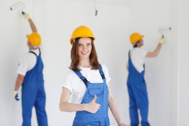 Duvarı boyayan üniformalı iki genç işçi