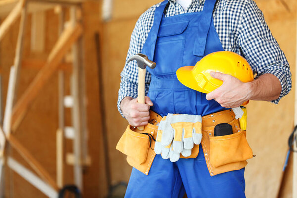 Construction worker at construction site holding hammer and hardhat