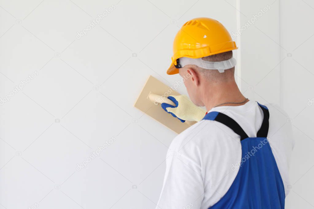 Builder working with grinding tool aligning wall indoors