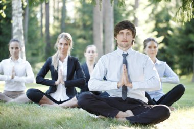 İş adamları parkta yoga yapıyor.
