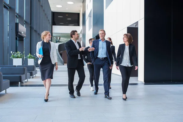 Équipe Affaires Animée Marchant Ensemble Dans Immeuble Bureaux Montrant Travail — Photo