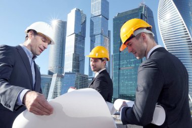 Gökdelenlerin arkaplanındaki planlara sahip mimarlar