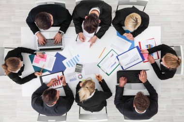 İş adamları ile tablolar ve masa etrafında oturup diyagram istatistikleri belgelerle çalışmak