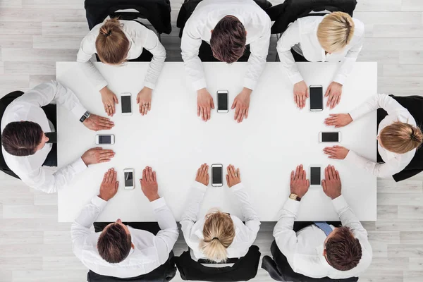 Деловые Люди Используют Смартфоны Сидя Вокруг Белого Стола — стоковое фото