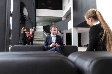 İş adamları ofis lobisindeki koltukta oturup sohbet ediyorlar. Mola, röportaj kavramı.