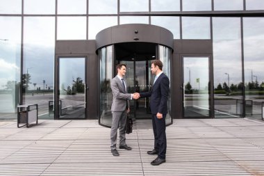 İş adamları ofis binasının dışında el sıkışıyor.