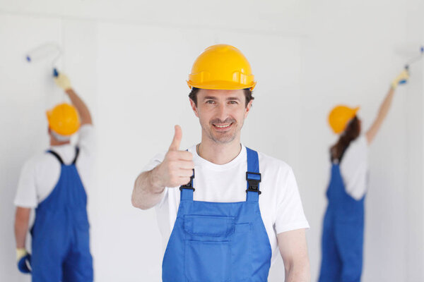 Workman gives thumbs up in front of two painters
