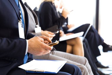 İşadamları cep telefonu kullanıyor. Eğitim odasında, konferans salonunda oturuyorlar.