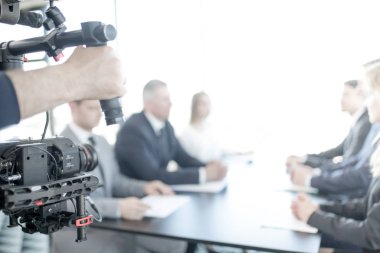 Düzenli kamera kullanan kameraman, toplantıdaki iş adamlarının videosunu çekiyor