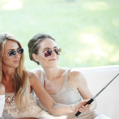 Genç ve güzel bayan arkadaşlar dışarıda selfie çekiyorlar.