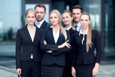 Başarılı iş adamlarının portresi modern ofis binasının yakınında birlikte duruyorlar.