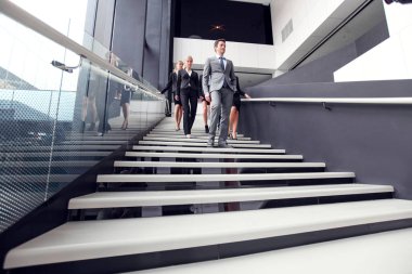 Bir grup iş adamı bir ofis binasında yürüyen ve merdivenlerde yürüyen