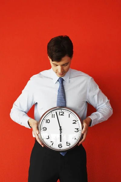 Hombre Negocios Sosteniendo Reloj Pared Sobre Fondo Rojo Carrera Contra — Foto de Stock
