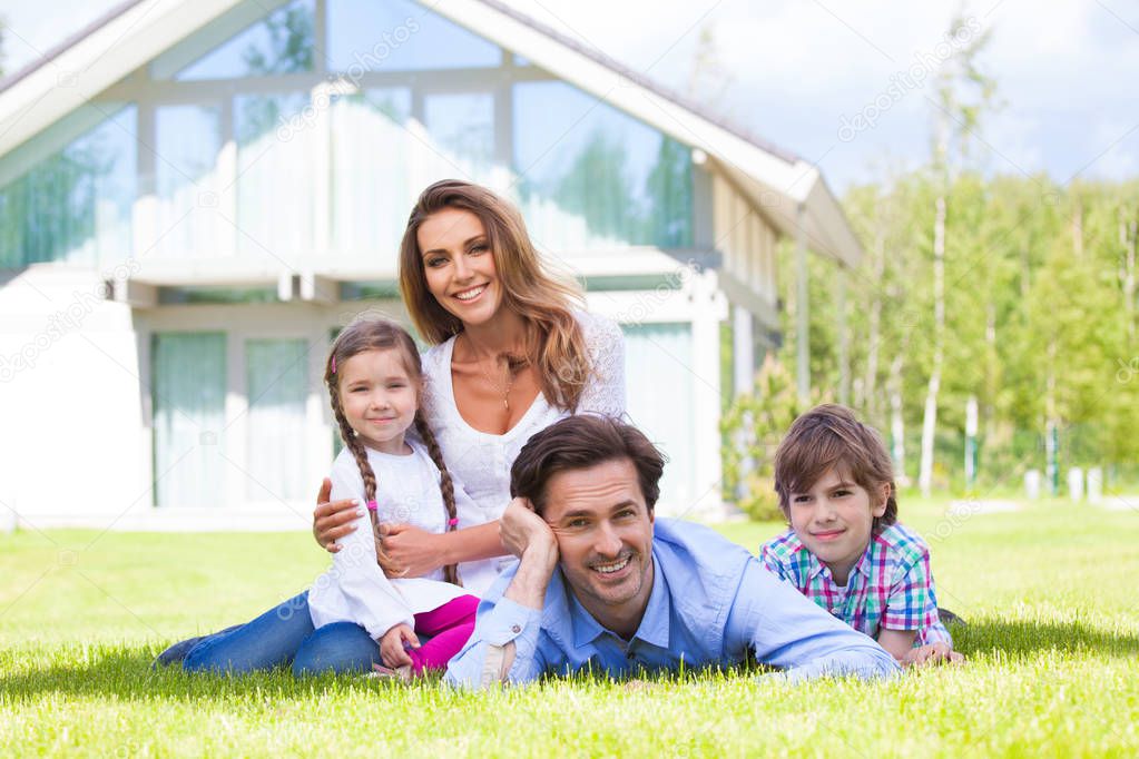 Happy family of parents and children in front of their house outdoors